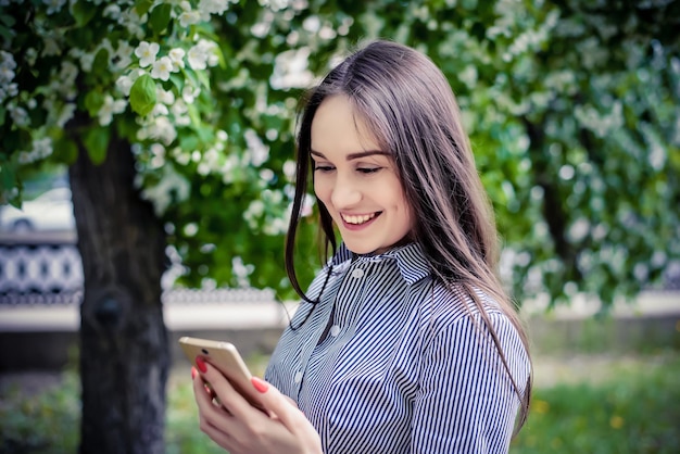 Een jong meisje kijkt naar de mobiele telefoon in het park