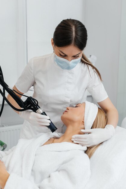 Een jong meisje krijgt een koolstofpeeling voor de huid van de nek in een schoonheidssalon laserpulsen reinigen de huid hardware cosmetologie het proces van fotothermolyse verwarmt de huid