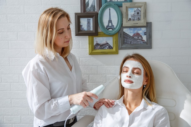 Een jong meisje maakt elektrische procedures in de salon van een schoonheidsspecialist