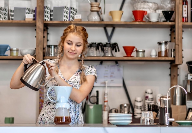 Een jong meisje maakt koffie in de keuken. Ze is in een goed humeur, ze glimlacht