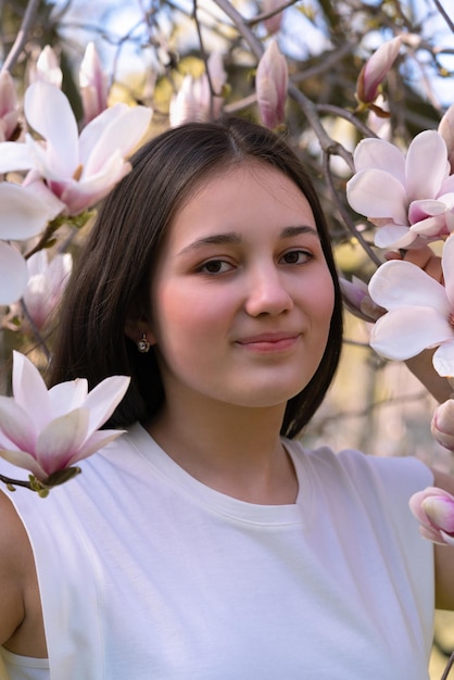 Een jong meisje met donker haar in roze magnolia bloemen Close Lente magnolia bloei