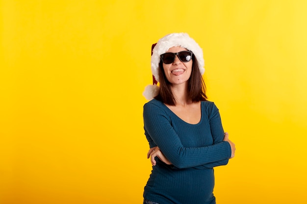 Een jong meisje met een zonnebril die naar de camera kijkt en een kerstmuts draagt