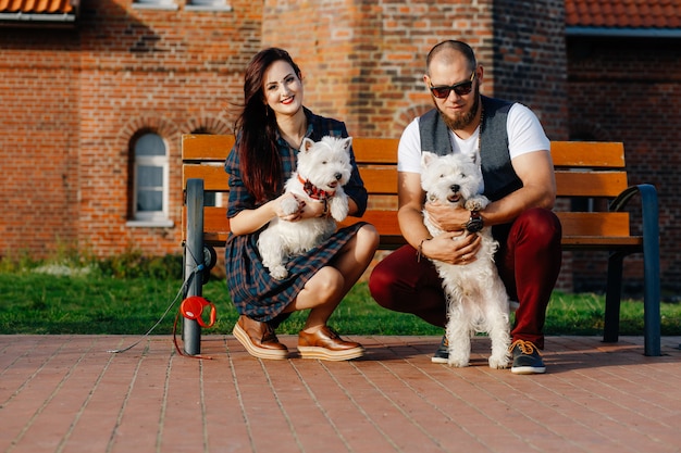 Een jong meisje met haar vriendje gehurkt met twee kleine witte puppy's