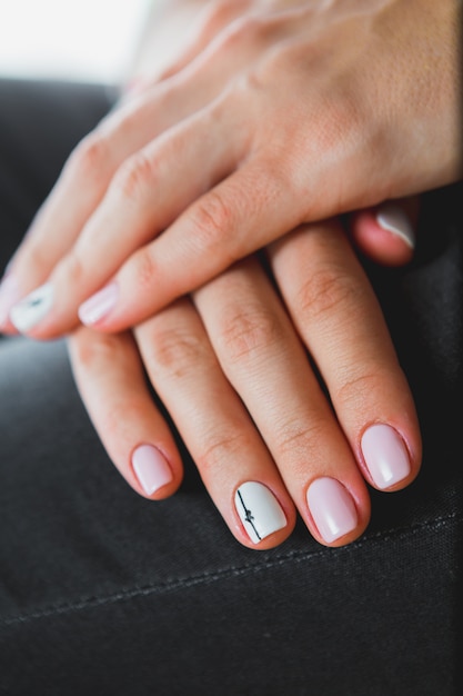 Een jong meisje met mooie witte manicure houdt een zwarte aktentas. Stijl van mode