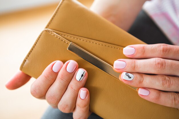 Een jong meisje met mooie witte manicure houdt een zwarte aktentas. Stijl van mode