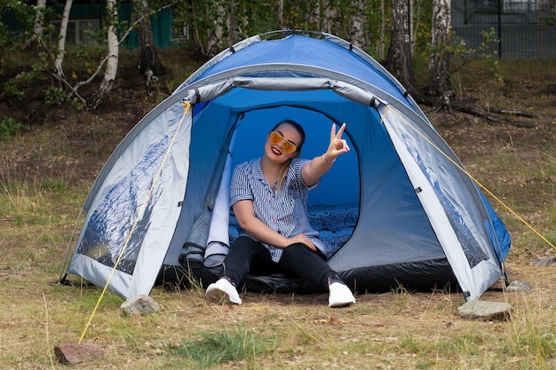 Een jong meisje met zonnebril zit in een tent in de natuur