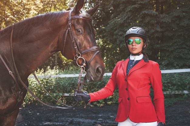 Een jong meisje praat en zorgt voor haar paard. ze houdt van de dieren en brengt haar tijd met plezier door in hun omgeving.