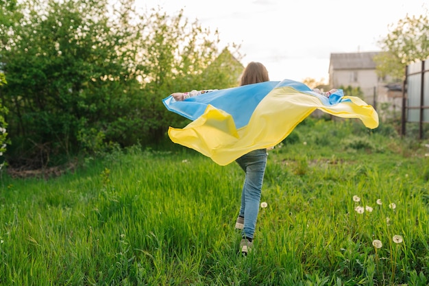 Foto een jong meisje rent met de oekraïense vlag foto van een meisje dat rent met een oekraïense vlag als cape