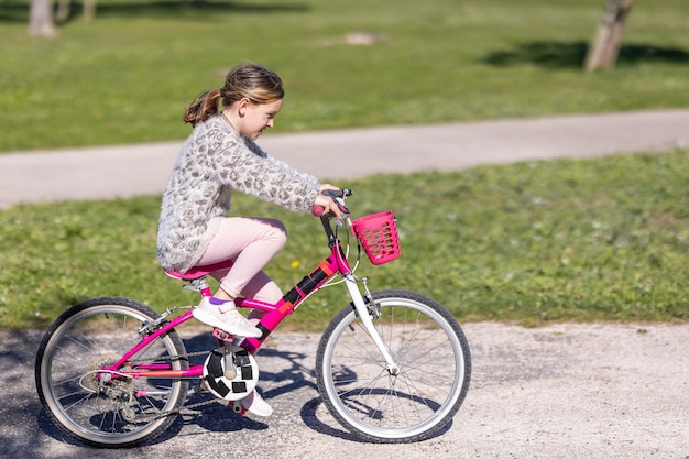 Een jong meisje rijdt op een roze fiets met een mand aan de voorkant