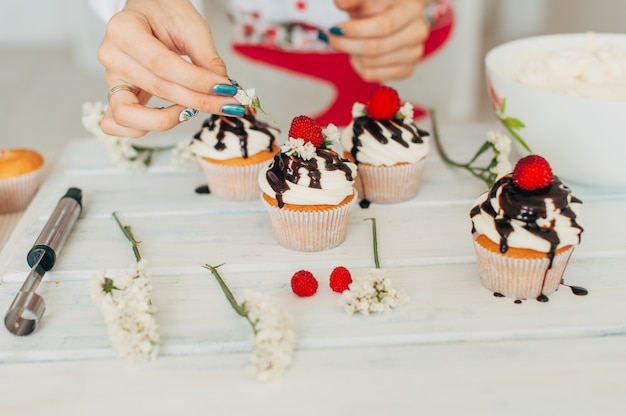 Foto een jong meisje siert cupcakes met verse bessen en bloemen