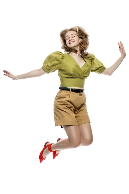 Een jong meisje springt stijlvolle tiener in beige korte broek en een vrouwelijke groene blouse activiteit en energie geïsoleerd op witte achtergrond vertical