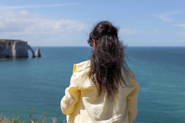 Een jong meisje tegen de achtergrond van de zee en wazige rotsen met een boog