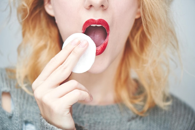 Een jong meisje veegt de rode lippenstift af, close-up