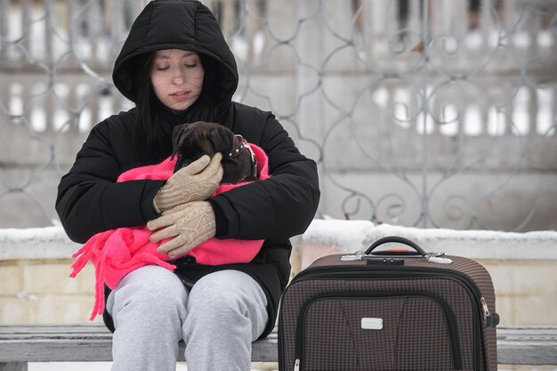 Een jong meisje verlaat haar stad met haar spullen en een puppy die op haar transport wacht