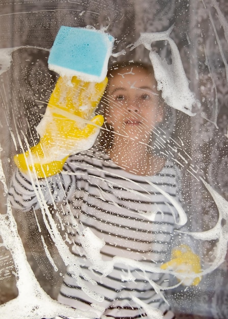 Een jong meisje wast de ramen van haar huis. Huiswerk. Helpen. Schoonmaak