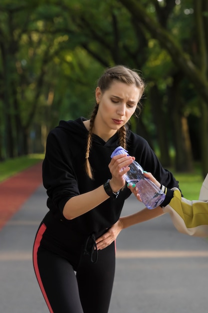 Een jong meisje werd tijdens het joggen in een park ziek en drinkt water.