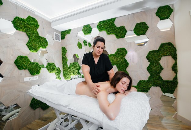 Een jong mooi meisje geniet van een professionele cosmetische massage in de Spa. Lichaamsverzorging. Schoonheidssalon.