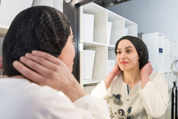 Een jong, mooi meisje kijkt in de spiegel naar het resultaat van het werk dat is gedaan met de permanente wenkbrauwprocedure