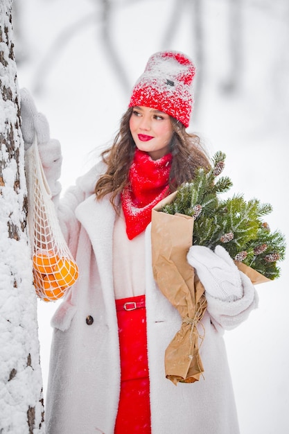 Een jong mooi meisje loopt op een winterdag in de tuin in haar handen met mandarijnen