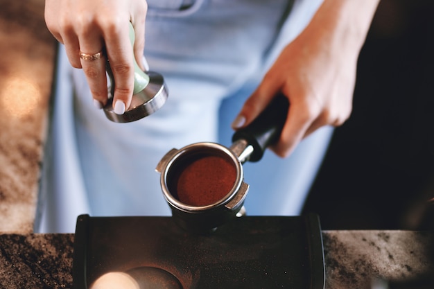 Een jong mooi slank meisje, gekleed in een casual outfit, kookt koffie in een moderne coffeeshop. Het richt zich op het proces. .