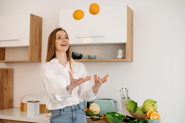 Een jong mooi vegetarisch meisje of blogger bereidt thuis in de keuken een ontbijt van fruit, groenten en groenten Blog over gezond eten