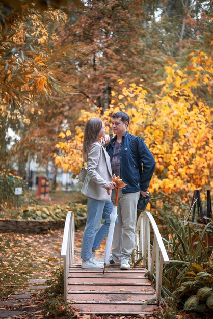 Een jong mooi verliefd stel gekleed in casual stijl in een herfstpark staat op een gouden herfstbrug