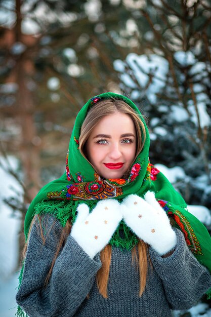 Een jong Oekraïens meisje in witte handschoenen en een volkssjaal in de winter Portret van een blonde