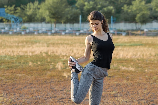 Een jong slank atletisch meisje in sportkleding met slangenprint voert een reeks oefeningen uit