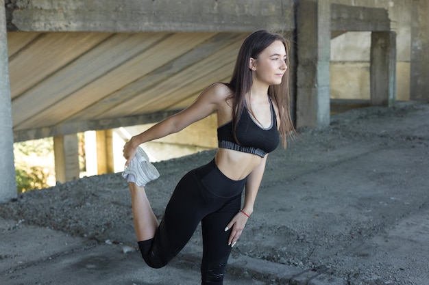 Een jong slank atletisch meisje in sportkleding voert een reeks oefeningen uit Fitness en een gezonde levensstijl