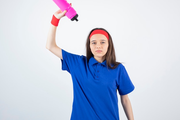 een jong sportief meisje dat roze fles water houdt.