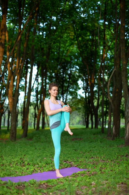 Een jong sportmeisje beoefent yoga in een rustig groen zomerbos