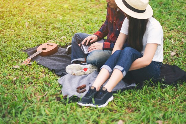 Een jong stel dat een laptop gebruikt en ernaar kijkt terwijl ze samen in het park zitten