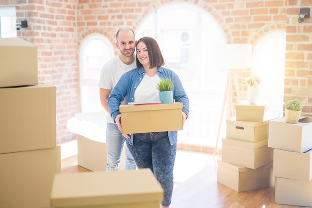 Een jong stel dat naar een nieuw huis verhuist, glimlacht en houdt kartonnen dozen vast