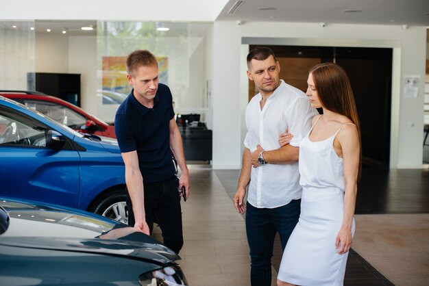 Een jong stel kiest een nieuwe auto bij de dealer en overlegt met een vertegenwoordiger van de dealer.