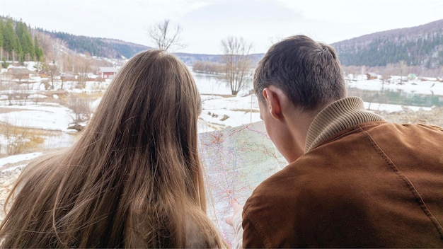 Een jong stel leert een routekaart terwijl ze een roadtrip-route bespreken