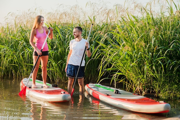 Een jong stel loopt langs de rivier op een opblaasbaar SUP-bord interessante communicatie