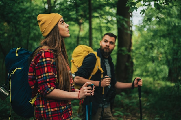 Een jong stel wandelaars die trekkingstokken gebruiken en rugzakken dragen