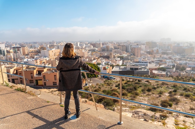 Een jong toeristisch meisje dat naar de stad kijkt vanuit het gezichtspunt van Cerro San Cristobal in de stad Almeria, Andalusië. Spanje. Costa del sol in de middellandse zee