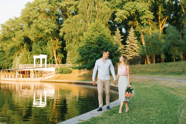 Een jong verliefd paar loopt langs de oever van een meer in een stadspark. eerste afspraakje