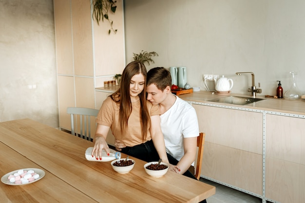 Een jong verliefd stel heeft samen thuis ontbijten in de keuken. Man en vrouw die graangewas met melk eten voor ontbijt.