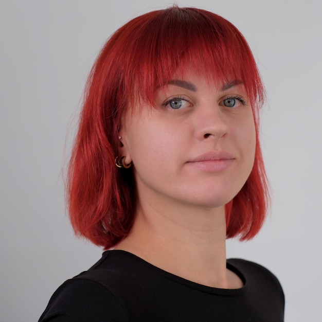 Foto een jonge aantrekkelijke vrouw met een kort oranje kapsel in een zwart t-shirt en spijkerbroek poserend in de studio op een witte achtergrond