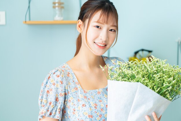 Een jonge Aziatische vrouw met bloemen in haar kamer