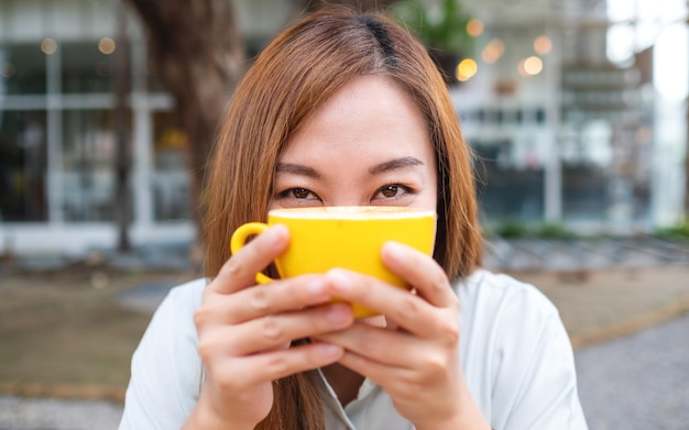 Een jonge Aziatische vrouw met een gele kop koffie
