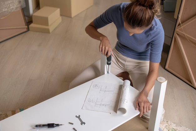 Foto een jonge aziatische vrouw monteert meubels nadat ze in een nieuw huis is verhuisd