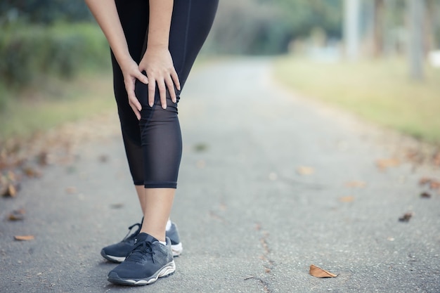 Een jonge Aziatische vrouw pijnlijke knieën na het hardlopen.