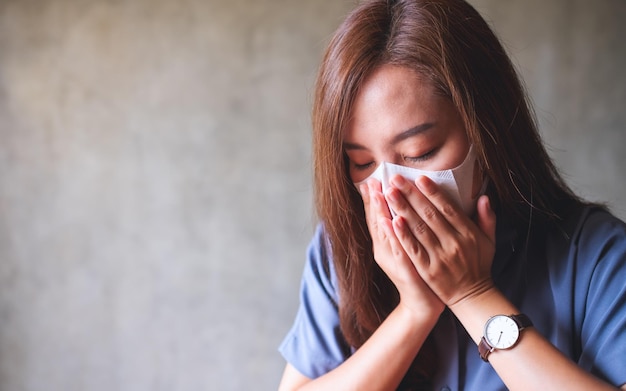 Een jonge Aziatische vrouw wordt ziek en draagt een beschermend gezichtsmasker voor de gezondheidszorg en het Covid19- of 2020-virusconcept