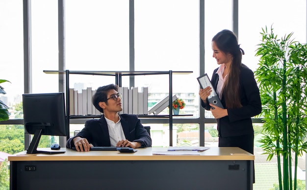 Een jonge Aziatische zakenman en een secretaresse op kantoor Samen werken tot voltooiing