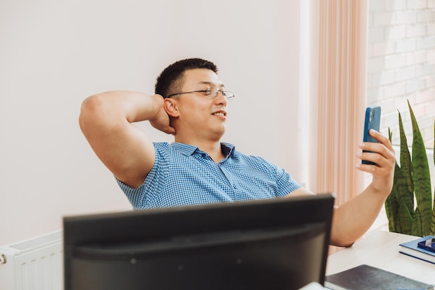 Een jonge Aziatische zakenman praat aan de telefoon om werk op kantoor te bespreken, de man is Aziatisch