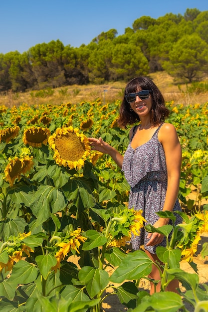 Een jonge blanke brunette geniet van enkele prachtige zonnebloemen