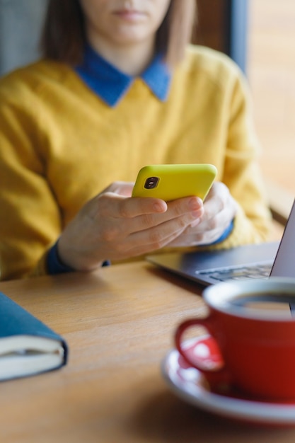 Een jonge blanke europese vrouw in een blauw denim shirt en bril werkt aan een laptop